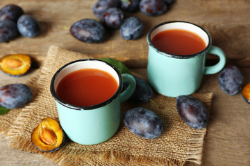 Plum Juice in mugs with fresh fruits