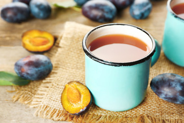 Plum Juice in mugs with fresh fruits