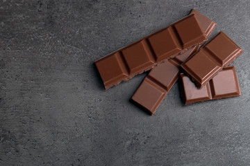 Milk chocolate pieces on gray background