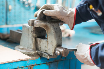 Worker securing a metal plate in a vise - obrazy, fototapety, plakaty