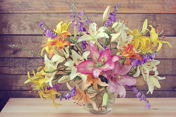Still life with a bouquet from lilies of different colors.