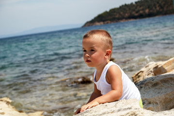 Fototapeta na wymiar Portrait of a little boy explores the rock beach