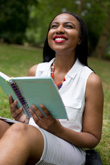 Fototapeta premium student sitting in the park holding her textbook