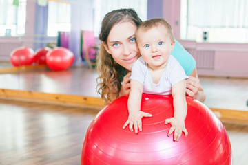 Mother with happy baby doing exercises with gymnastic ball