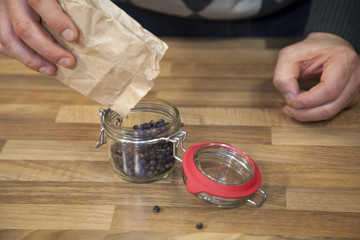 Man pouring peppercorn in a jar.