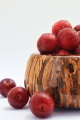 Plums in in wooden bowl covered with water droplets.