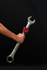 Man Holding a Big Wrench with a Red Christmas Bow.