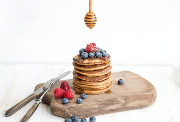 Buckwheat pancakes with fresh berries and honey on rustic wooden