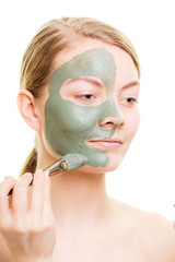 Woman applying with brush clay mud mask her face