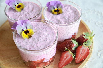 Obraz na płótnie Canvas Homemade pink Chia pudding with strawberry and edible flowers