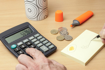 person with money at a desk using a calculator and pen