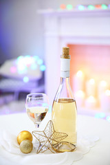 Bottle and glass of wine with Christmas decor against colorful bokeh lights background