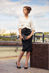 Young fashion business woman with handbag on the city street