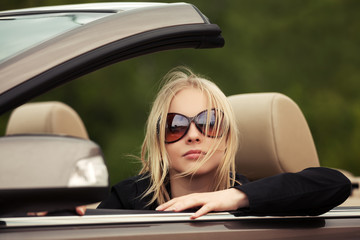 Fototapeta na wymiar Young fashion woman in sunglasses driving convertible car