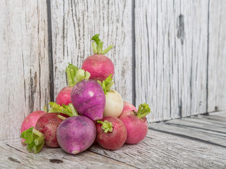 Pink, dark red, red, and purple radish over wooden background