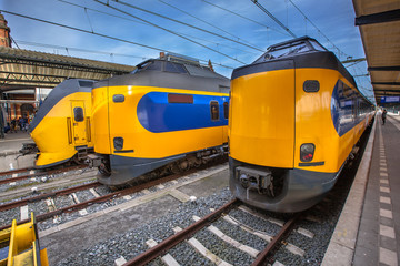 Three modern passenger commuter trains waiting at a historic sta