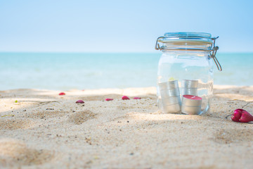 Candles in jar with beautiful beach and sea in background.