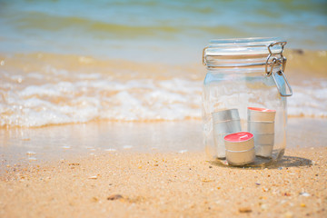 Candles in jar with beautiful beach and sea in background
