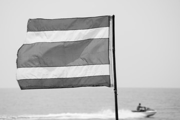 Thai flag on the beach with jetski in background  - monochrome