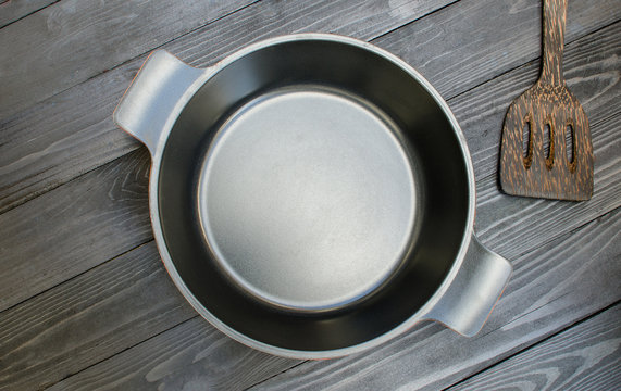 Flat bottom pan and flipper used in frying on  black wooden back