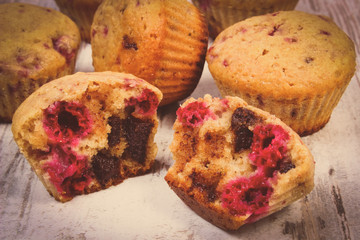 Vintage photo, Fresh baked muffins with chocolate and raspberries on wooden background, delicious dessert