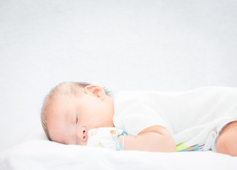 Peaceful baby lying on a bed while sleeping.