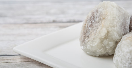 Fototapeta na wymiar Japanese confection, round glutinous rice stuffed with sweetened red bean paste or locally known as daifukumochi in a white plate over wooden background