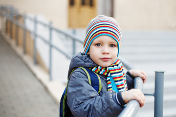 Beautiful little boy in bright striped hat and scarf