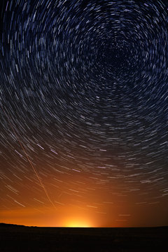 Star trail in the night sky against the backdrop of city lightin