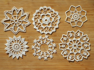 Crocheted snow flakes on a wooden background.