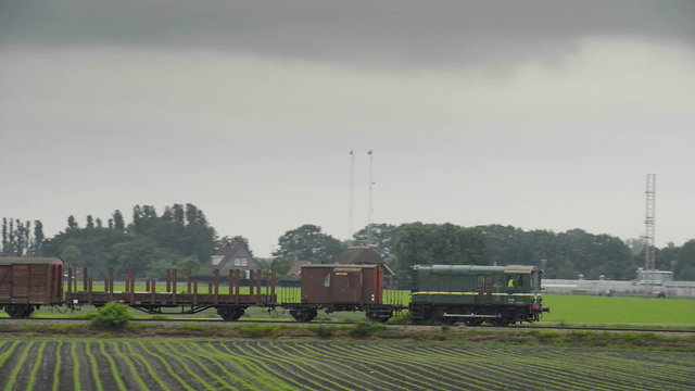 Old diesel freight train pulling various railroad cars in the countryside.