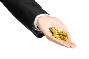 Fototapeta premium Money and business topic: hand in a black suit holding a pile of gold coins in the studio on a white background isolated