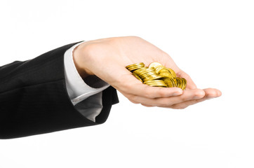 Money and business topic: hand in a black suit holding a pile of gold coins in the studio on a white background isolated