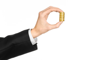 Fototapeta premium Money and business topic: hand in a black suit holding a pile of gold coins in the studio on a white background isolated