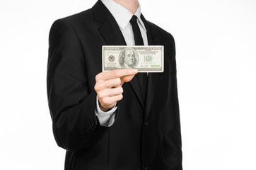 Money and business theme: a man in a black suit holding a bill of 100 dollars and features a hand gesture on an isolated white background in studio