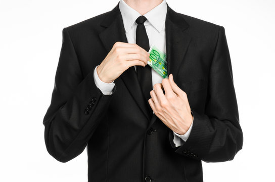 Money and business theme: a man in a black suit holding a bill of 100 euros and shows a hand gesture on an isolated white background in studio