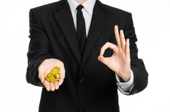Money and business theme: a man in a black suit holding a pile of gold coins in the studio on a white background isolated