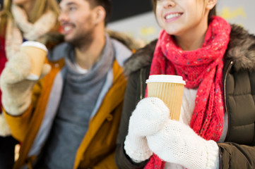 Obraz premium happy friends with coffee cups on skating rink