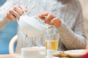 close up of man with pot pouring tea at cafe