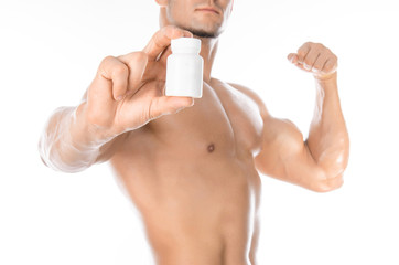 Fototapeta premium Bodybuilding and chemical additives: handsome strong bodybuilder holding a white jar of pills on white isolated background in studio