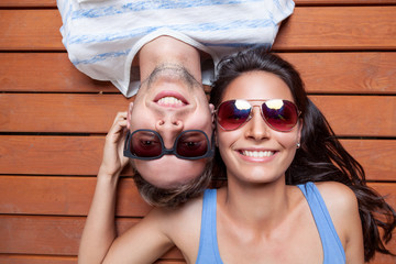 Happy young couple lying on a wooden floor