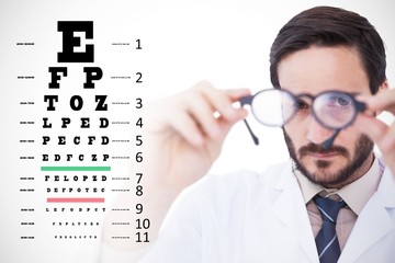 Composite image of doctor looking through eyeglasses