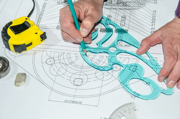 engineering drawings with human hands drawing a project by pencil on paper