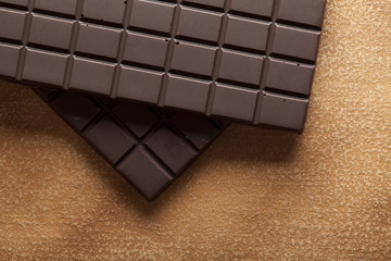 Dark chocolate bar on brown handmade paper background