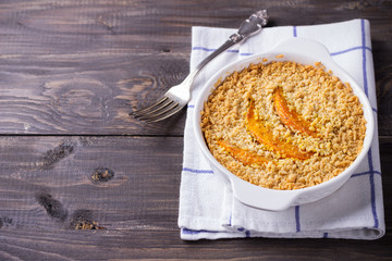 Crumble with pumpkin and cheese in white dish on the wooden table