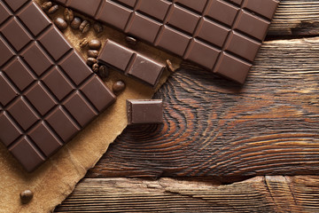 Dark homemade chocolate on wooden and paper background