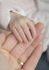manina di neonato che stringe una mano grande