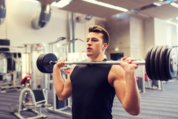 young man flexing muscles with barbell in gym