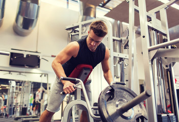 Fototapeta na wymiar young man exercising on t-bar row machine in gym