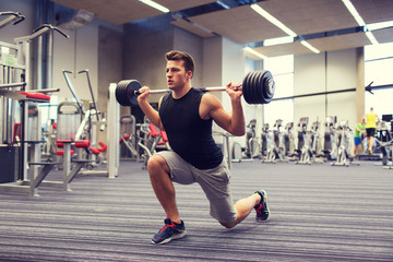 young man flexing muscles with barbell in gym - obrazy, fototapety, plakaty